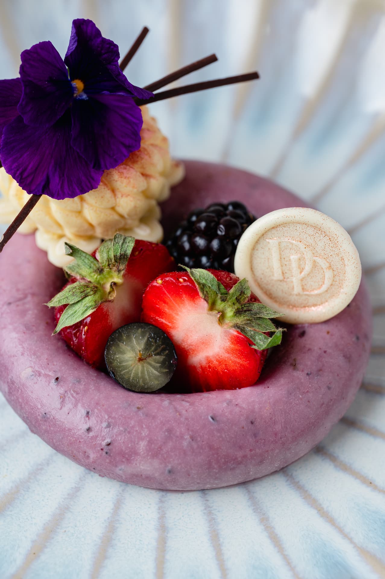 Paars dessert met verse bessen en eetbare viooltjes