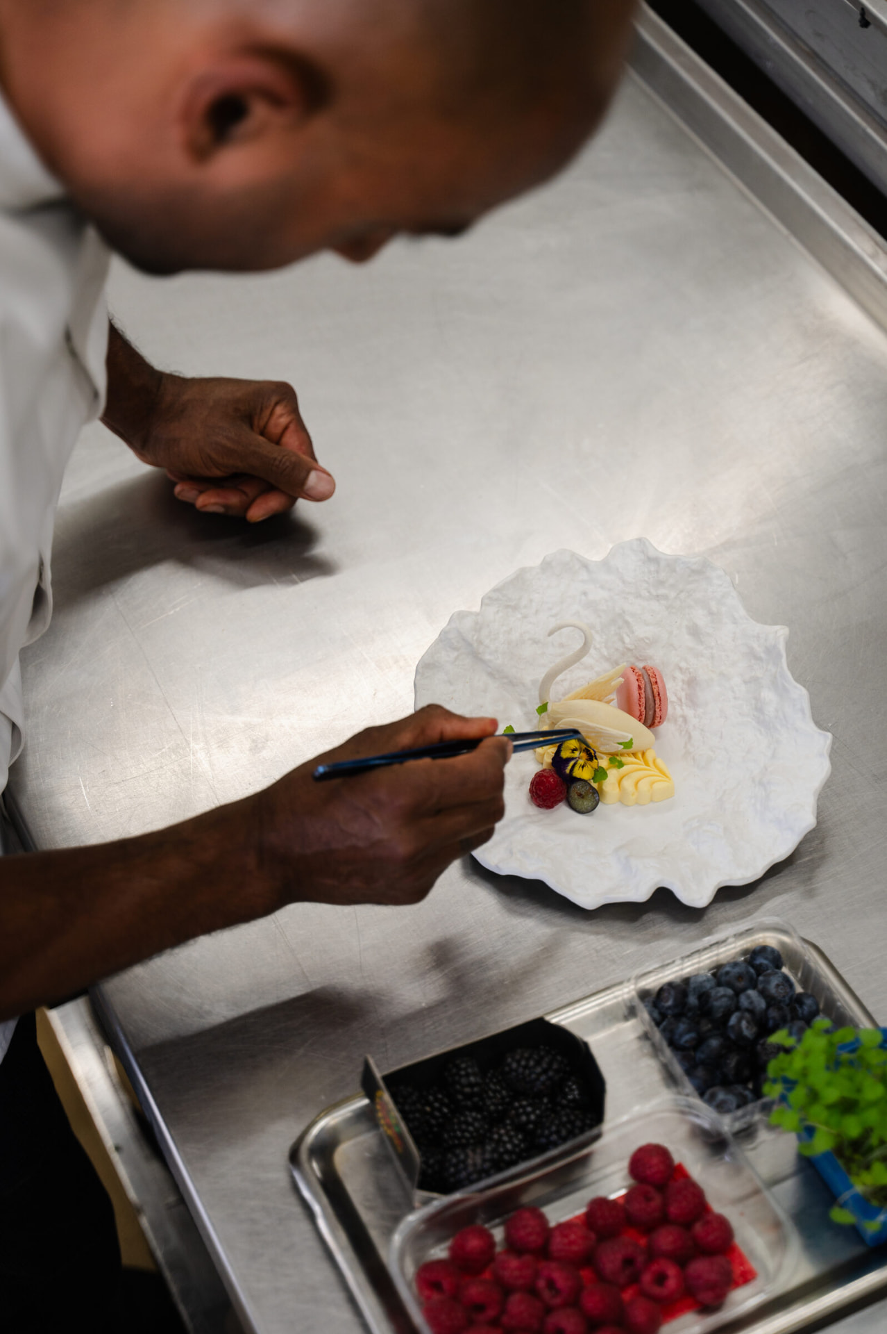 Handen werken een dessert af met vers fruit