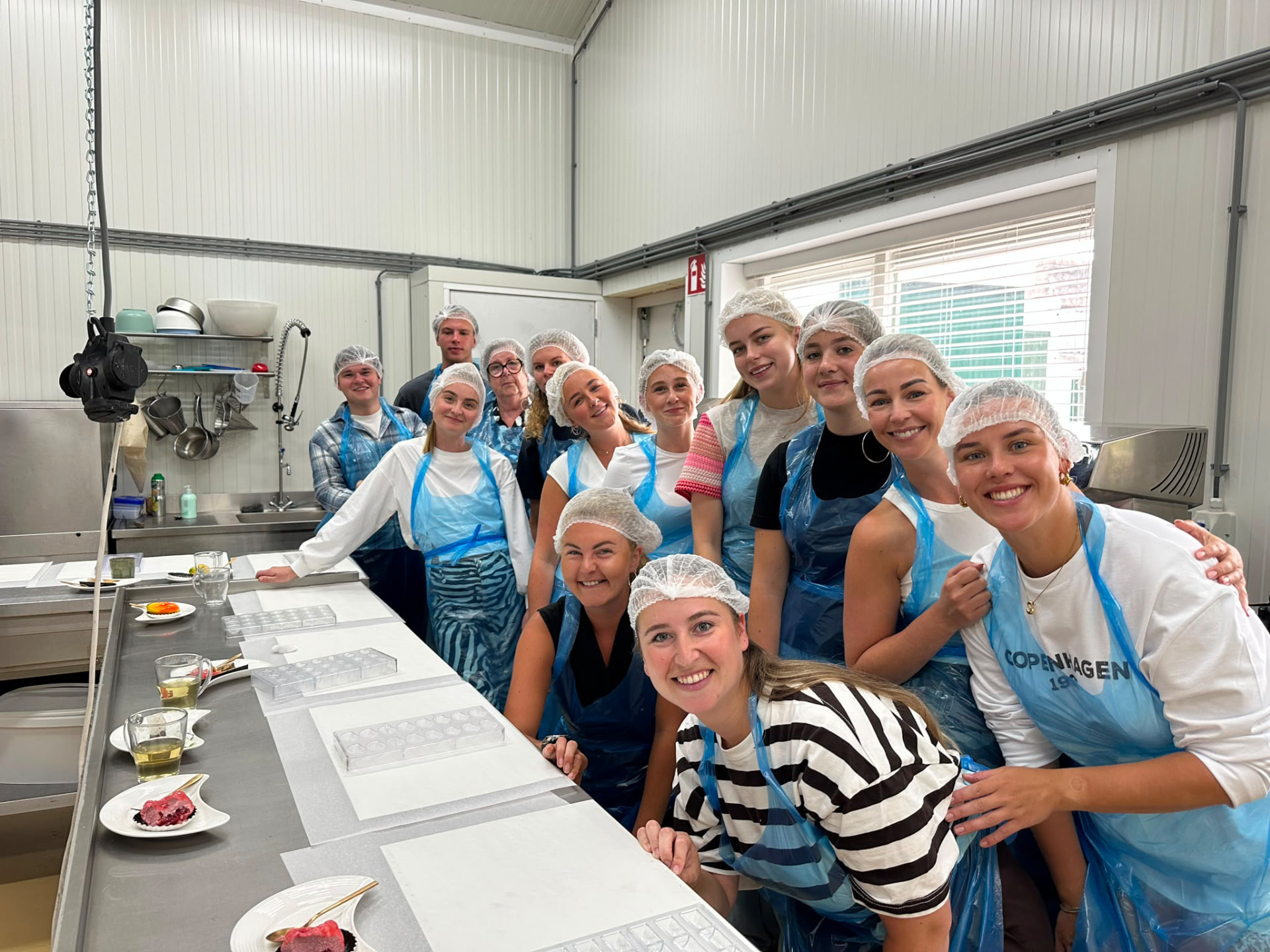 Groep deelnemers in schorten en haarnetjes tijdens een workshop op locatie